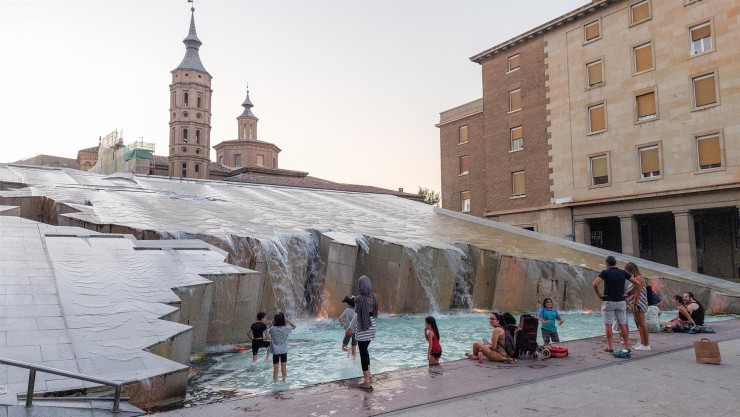 Un grupo de personas se bañan en una fuente en la plaza del Pilar de Zaragoza. / EFE