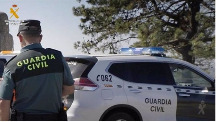 Un agente de la Guardia Civil junto a un coche oficial. / Guardia Civil.